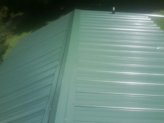 New green metal panels meeting at the ridge of a roof — Flat Roof Repair work by our crew in Cupertino
