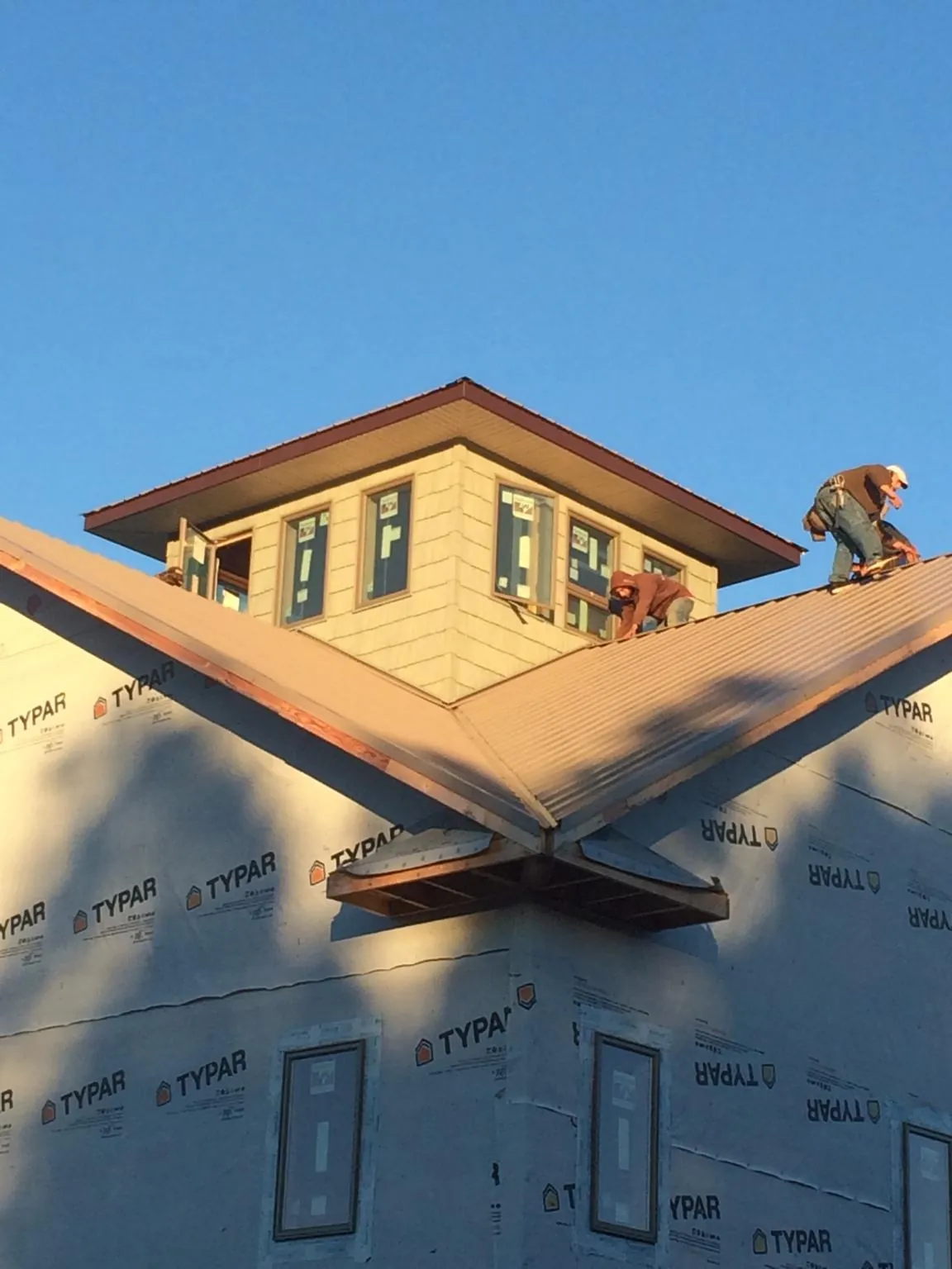 Roofers working around a rooftop cupola on a new metal roof at sunset — Roof Waterproofing in Cupertino by Roofing Brothers